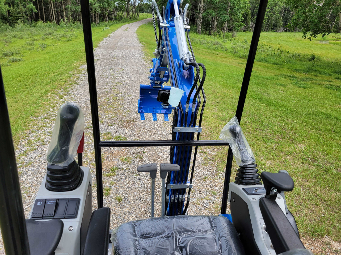 operator cabin view of 1.2 ton mini
excavator with joystick controls and
boom arm on gravel path for rent in
Calgary Alberta