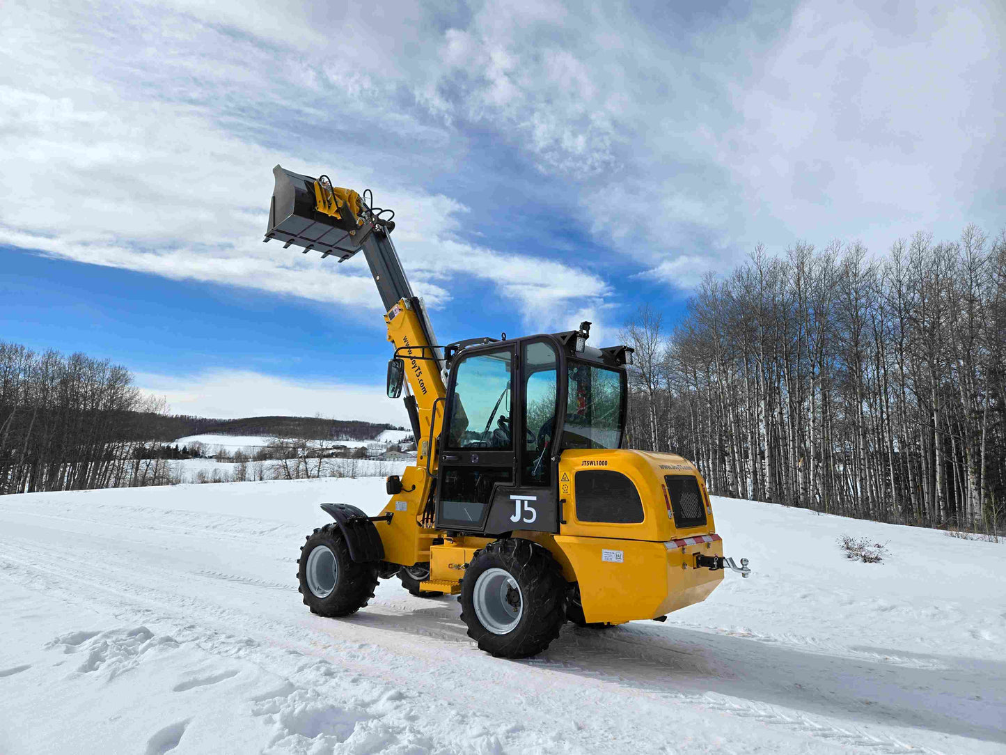 JT5WL1000 compact wheel loader 1 ton 2200 lbs rear side angle view with raised bucket in snowy field