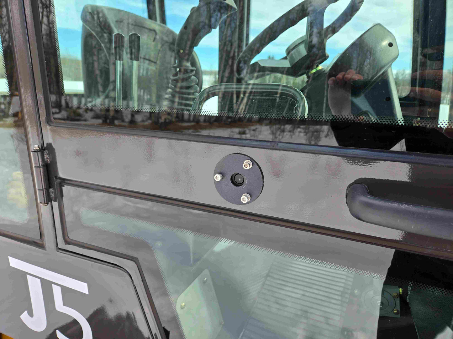 Close-up view of JT5 wheel loader cabin door locking mechanism and handle.