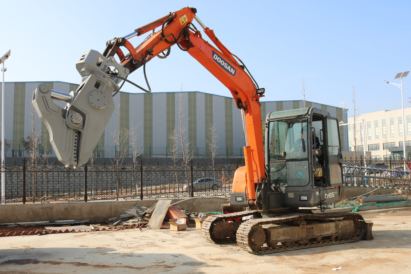 Doosan excavator equipped with a heavy-duty hydraulic demolition shear at a construction site.