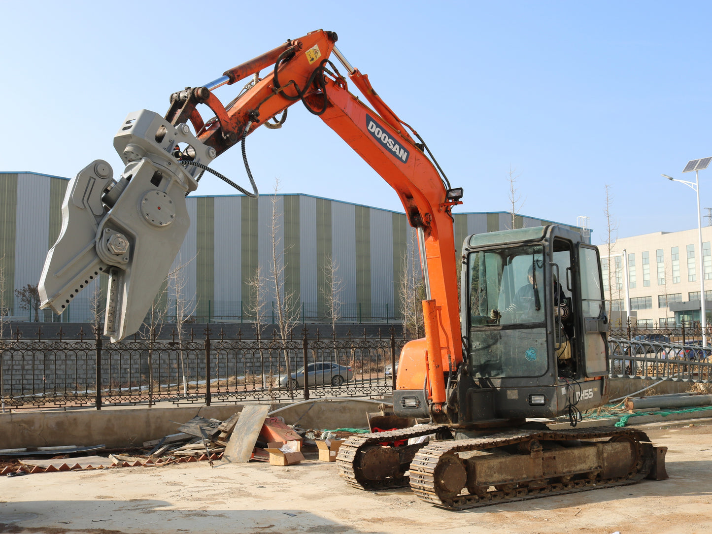 Excavator with rotating hydraulic shear attachment for demolition work.