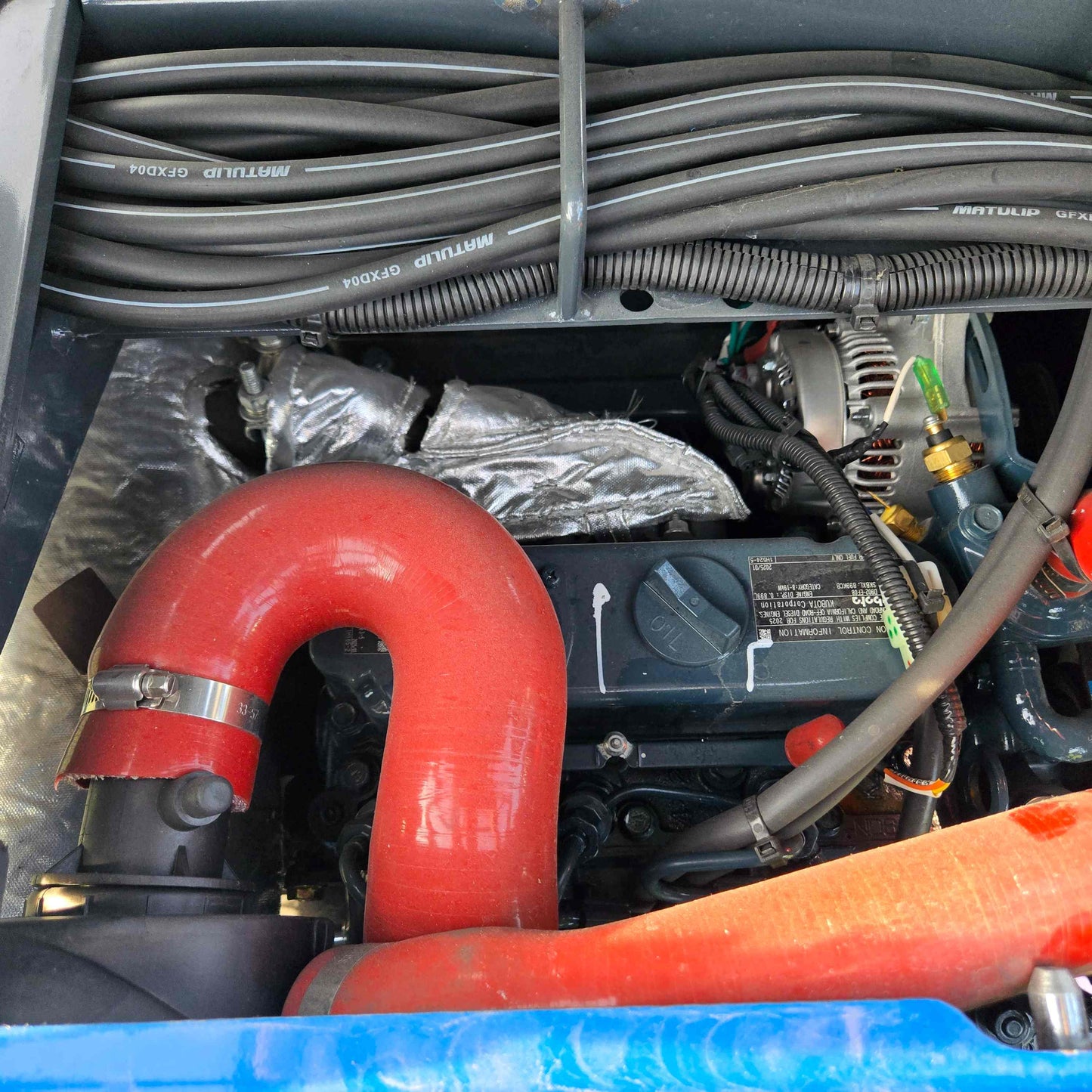 Close-up of JoyT5 Rippa R18 Mini Excavator engine with red air intake pipe, alternator and wiring