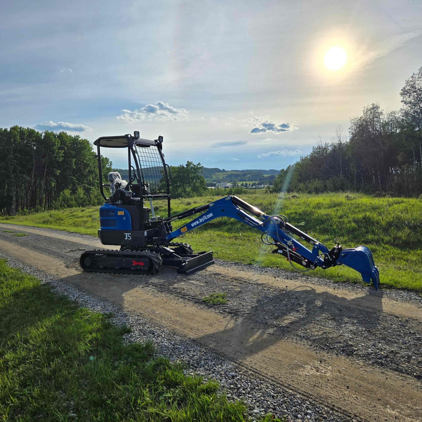 JoyT5 Rippa R18 Mini Excavator with fully extended arm working on dirt road at sunset