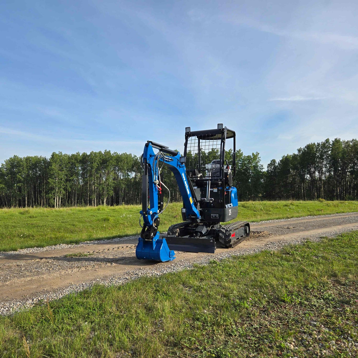 Front view of JoyT5 Rippa R18 Mini Excavator with bucket, hydraulic arm, and operator cabin on a gravel path