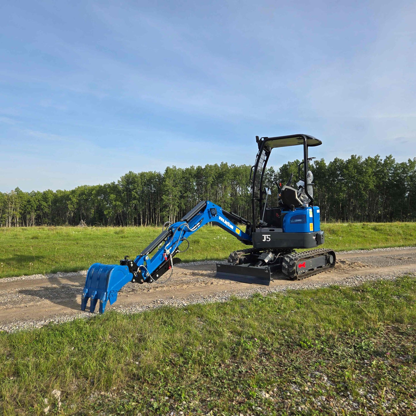 Side view of JoyT5 Rippa R18 Mini Excavator with digging bucket lowered to the ground on a gravel path