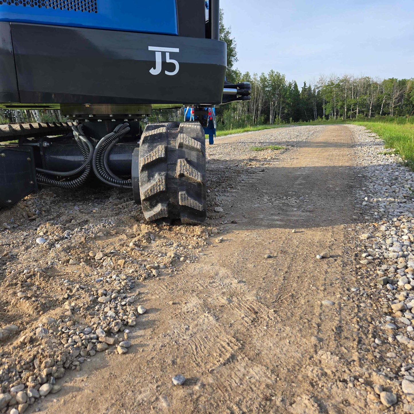 Close-up view of JoyT5 Rippa R18 Mini Excavator track and undercarriage on gravel road