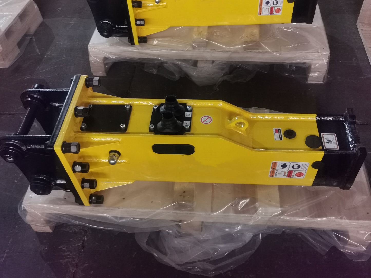 Heavy-duty yellow JoyT5 hydraulic breaker hammer attachment for excavator placed on wooden pallet with protective plastic wrap
