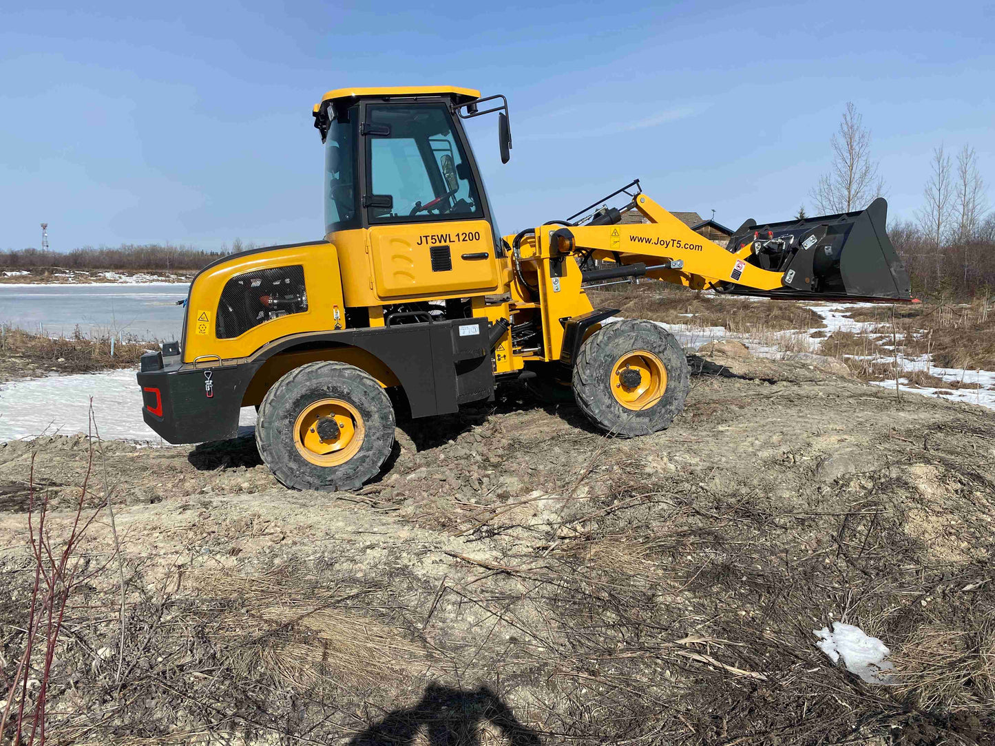 JT5WL1200 compact wheel loader working on uneven ground near construction site - small loader for farming and landscaping