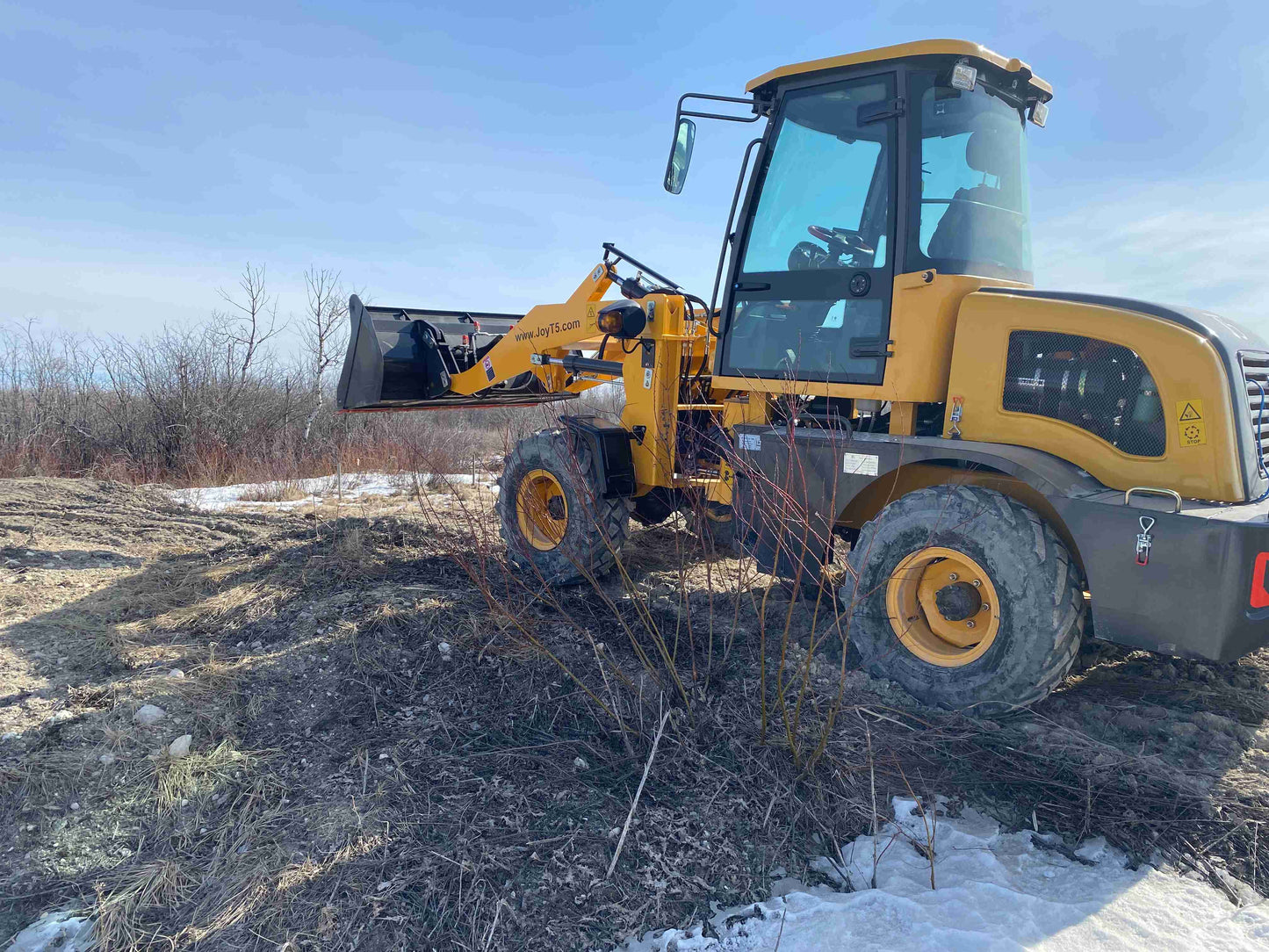 JT5WL1200 1.2 ton wheel loader with front bucket working on uneven ground - compact construction loader for landscaping and farming in Canada