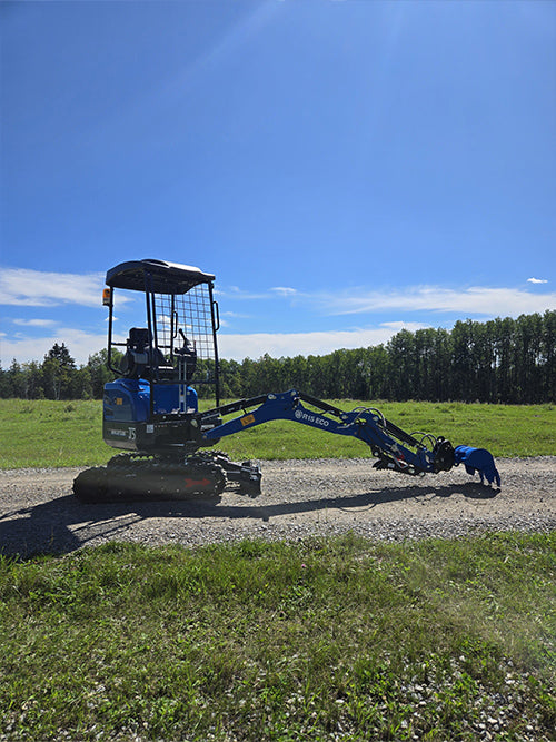 Side view of rippa r15 mini excavator for sale on gravel road with green field and blue sky background