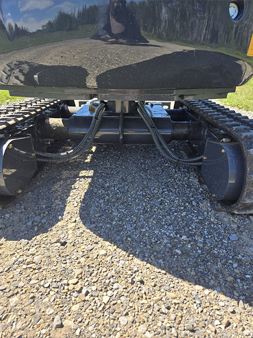 Undercarriage view of rippa r15 mini excavator for sale with hydraulic lines and track motors on gravel ground