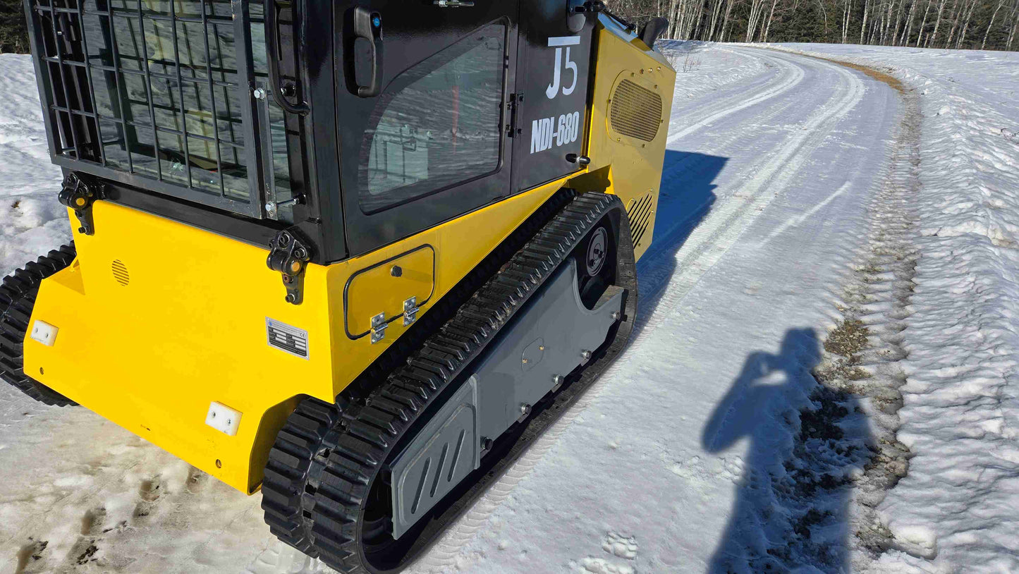 Rear side view of Rippa NDI680 skid steer loader showing track system and cabin design on snowy terrain | JoyT5