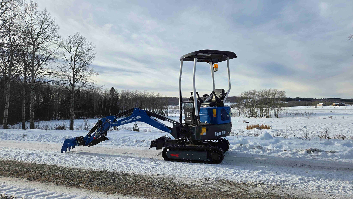 Rippa R10 Mini Excavator on snowy road with digging arm lowered close to ground | JoyT5