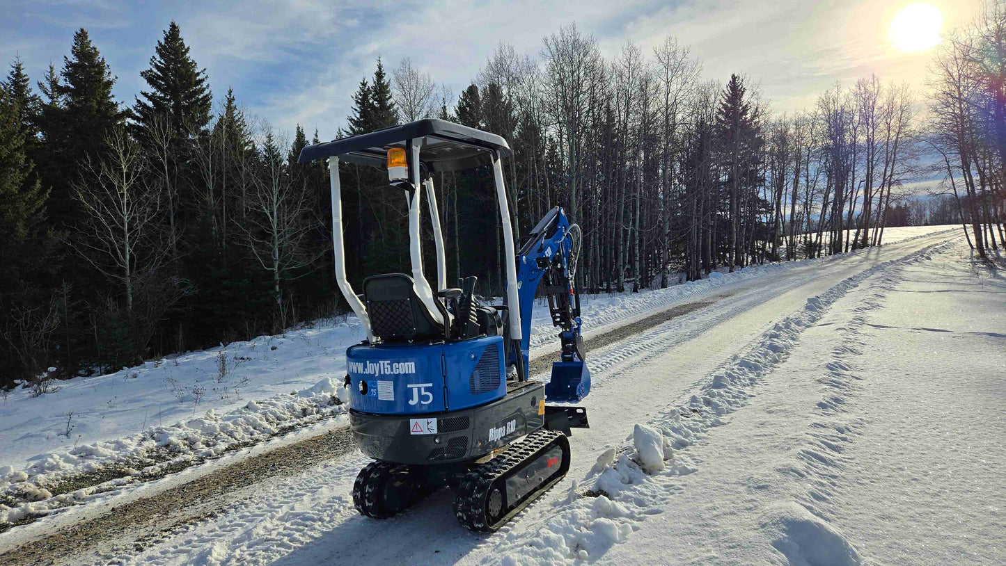Rippa R10 Mini Excavator parked on snowy road with sunset and forest background