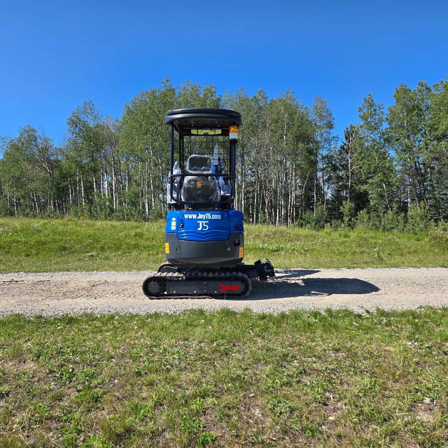 Rippa R15 Mini Excavator For Sale – direct rear view of compact excavator parked on a gravel road with forest background.