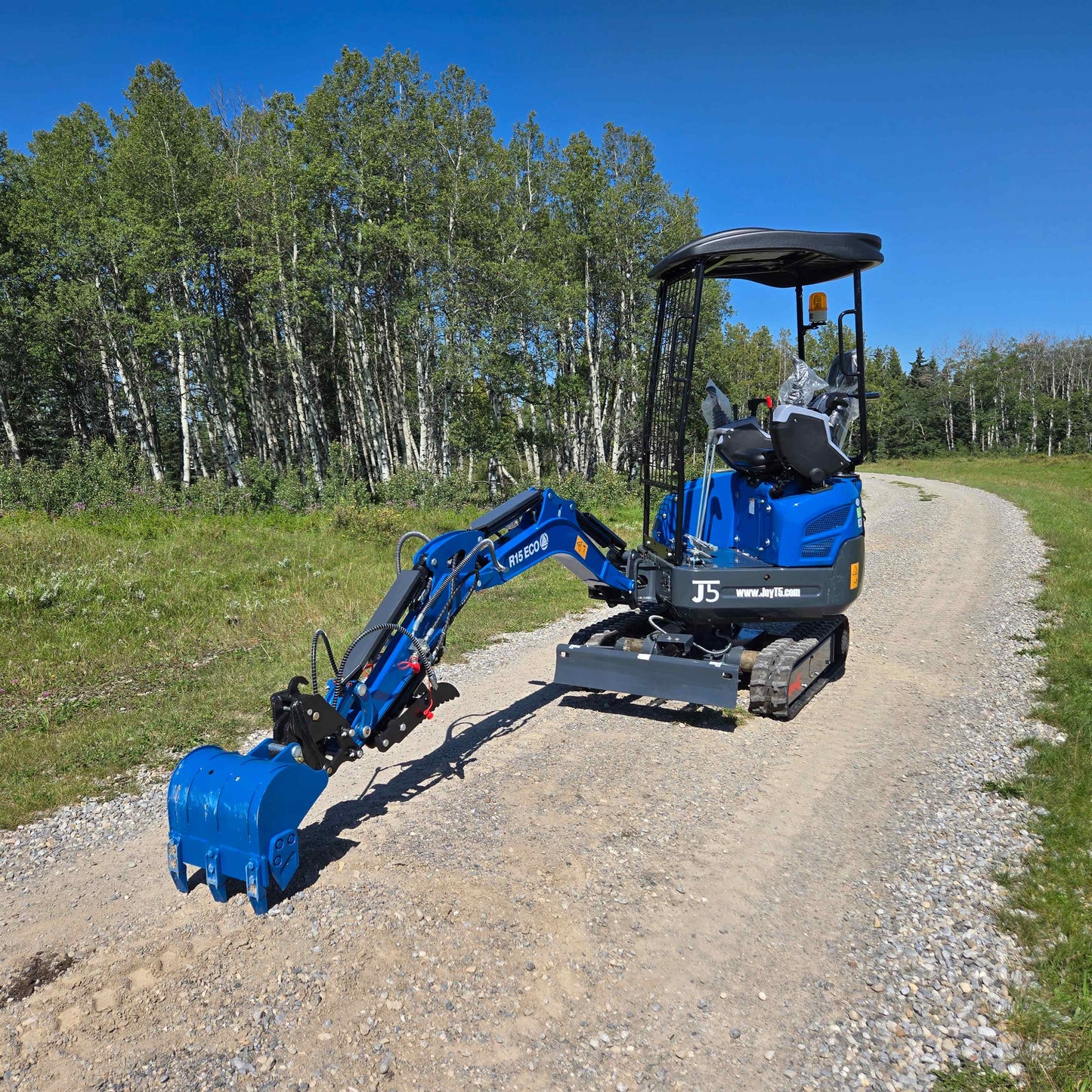 Rippa R15 Mini Excavator For Sale – side angle view with digging arm and bucket extended on gravel road.