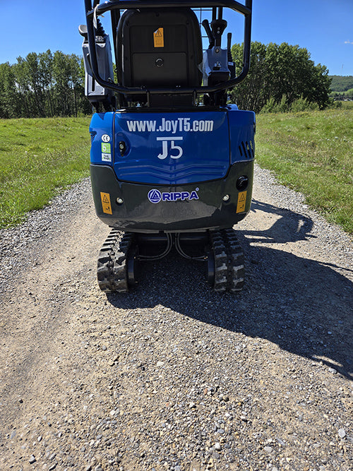 Rear view of Rippa R15 mini excavator on gravel road showing tracks and logo