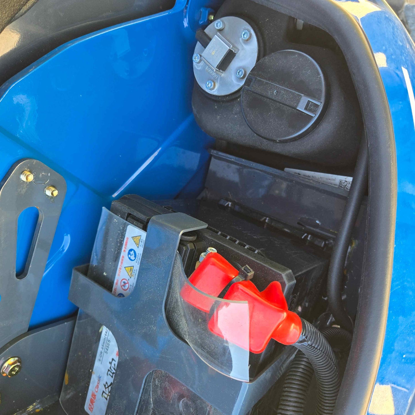 Rippa R22 Mini Excavator for sale battery compartment with protective red cover and fuel tank cap inside engine bay.