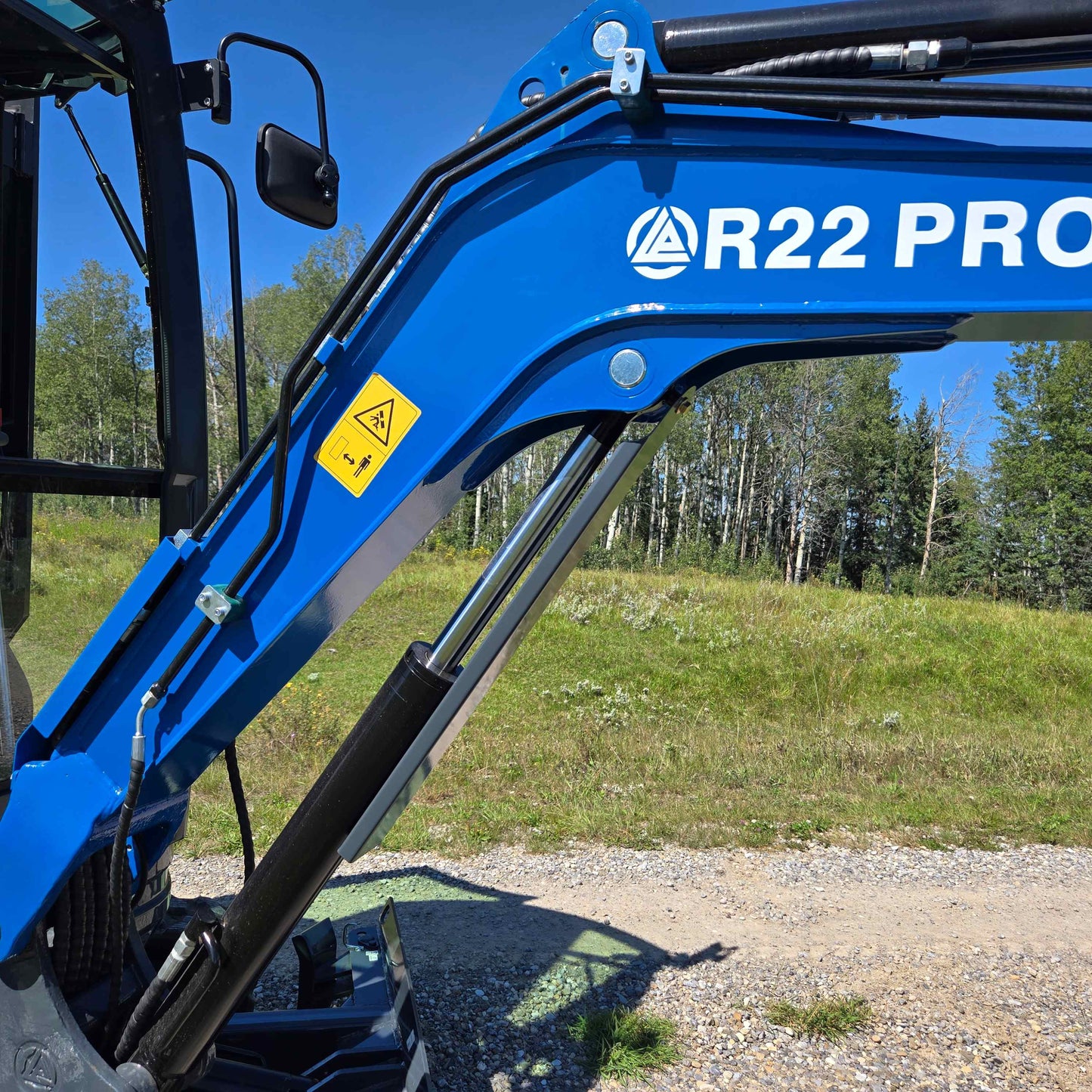 Rippa R22 mini excavator for sale boom showing hydraulic cylinder, hoses, and safety label for stable lifting performance.
