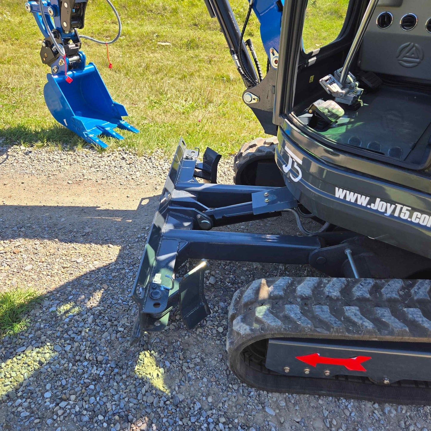 Close-up of Rippa R22 Mini Excavator for sale showing dozer blade, rubber tracks, and part of the digging bucket on gravel ground.