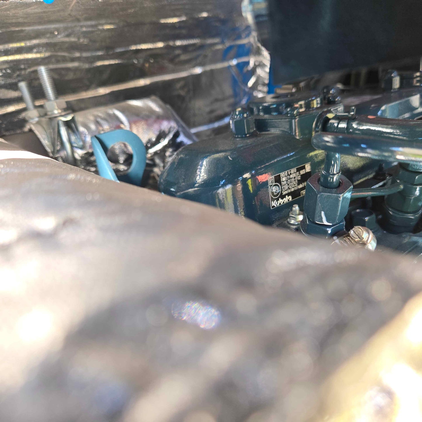 Close-up view of the Rippa R22 mini excavator for sale engine showing the metal serial plate with technical details in Chinese, partially covered by surrounding engine parts.