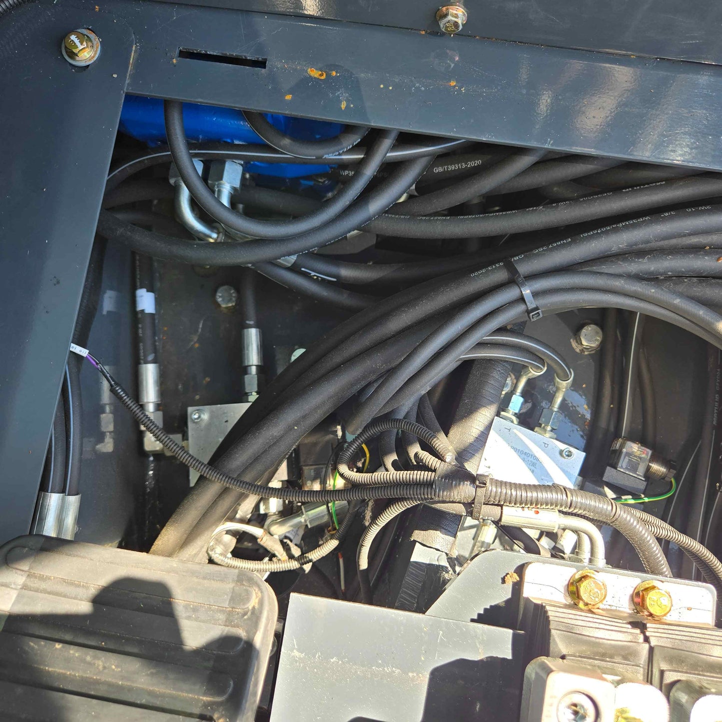 Close-up view of Rippa R22 Mini Excavator for sale hydraulic hoses, electrical wiring, and valve connections inside the machine compartment.