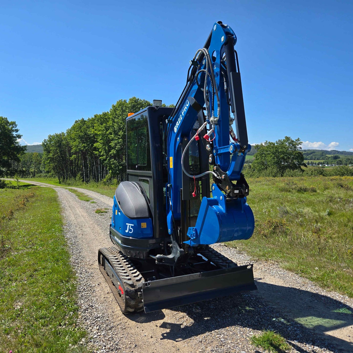 Rippa R22 Mini Excavator for sale with bucket attachment on a gravel rural road in a green field.