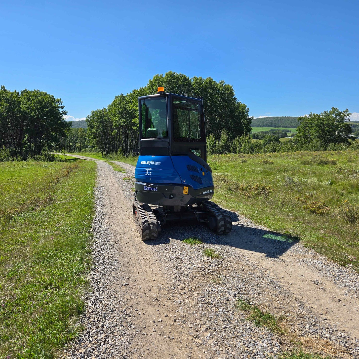 Rippa R22 Mini Excavator for sale rear angle view parked on a gravel road with trees in the background.