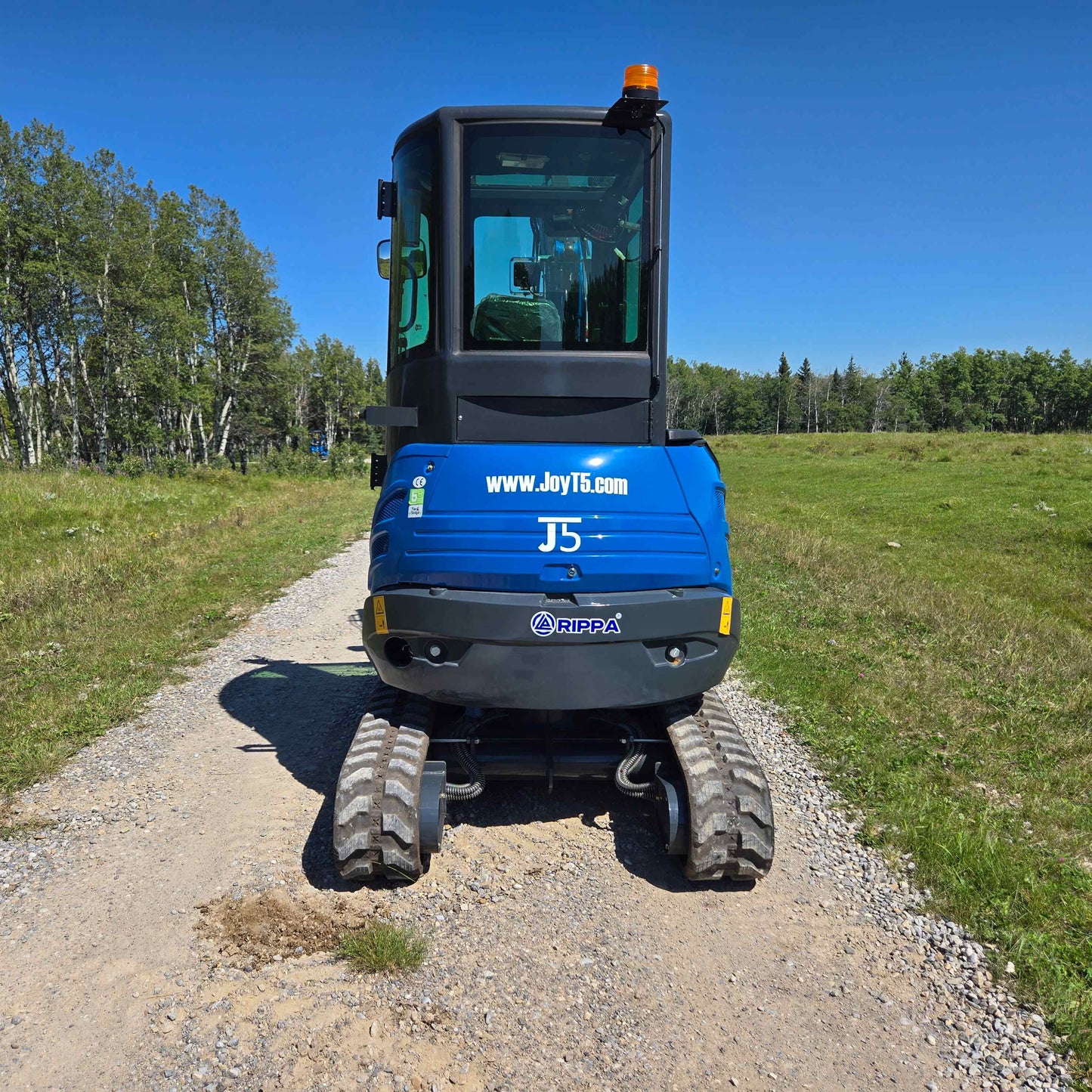 Rear view of the Rippa R22 Mini Excavator for sale parked on a gravel path in a field.