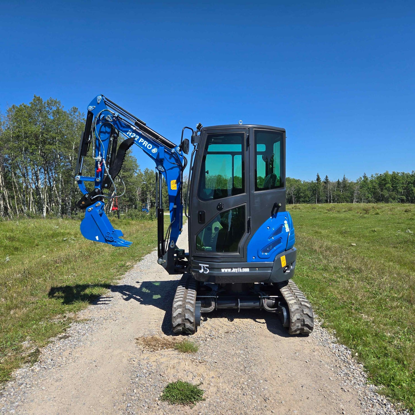 Side view of the Rippa R22 Mini Excavator for sale with cabin and boom arm extended on a gravel path.