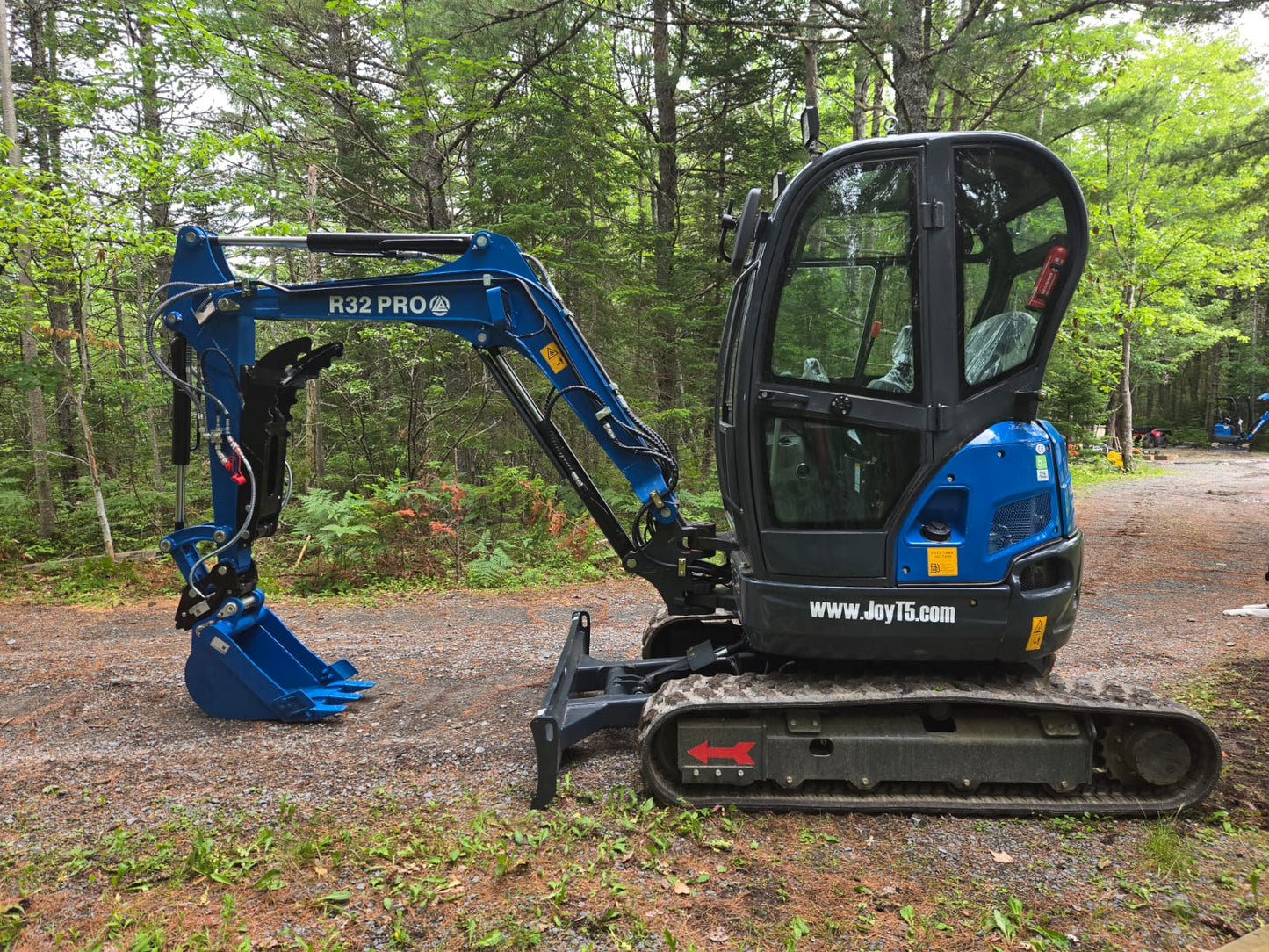 Side view of Rippa R32 Mini Excavator with enclosed cab and hydraulic arm in Canada | JoyT5