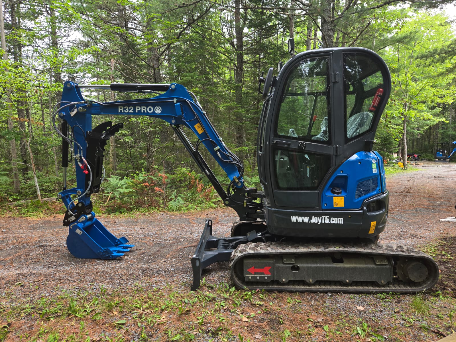 Side view of Rippa R32 Mini Excavator with enclosed cab and hydraulic arm in Canada |  JoyT5