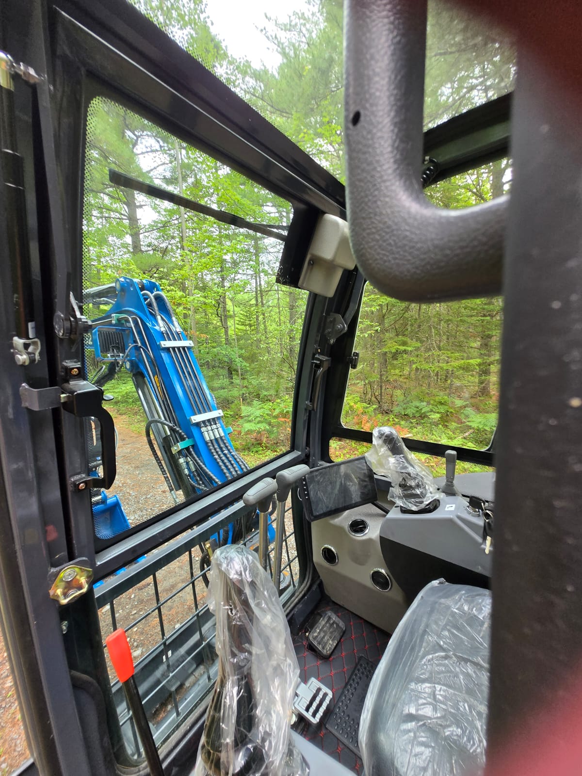 Operator view inside the Rippa R32 Mini Excavator cab showing seat, joystick controls, pedals, and boom visibility – JoyT5 Canada
