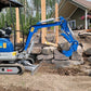 JoyT5 1.2 ton mini excavator for rent in Calgary, Alberta, compact excavator operating on a residential landscaping and stone construction project in Canada.