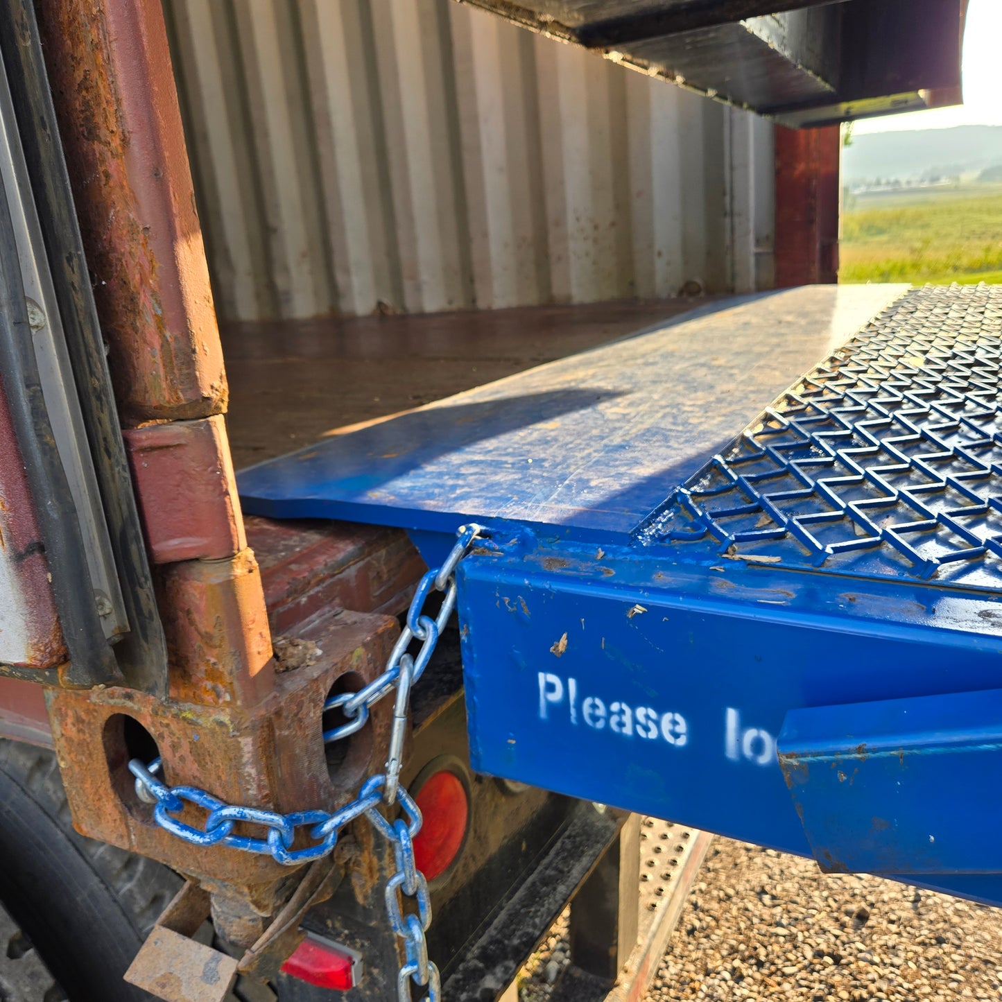 Close up view of twelve ton blue steel mobile loading ramp securely connected to truck container for safe forklift loading in Canada
