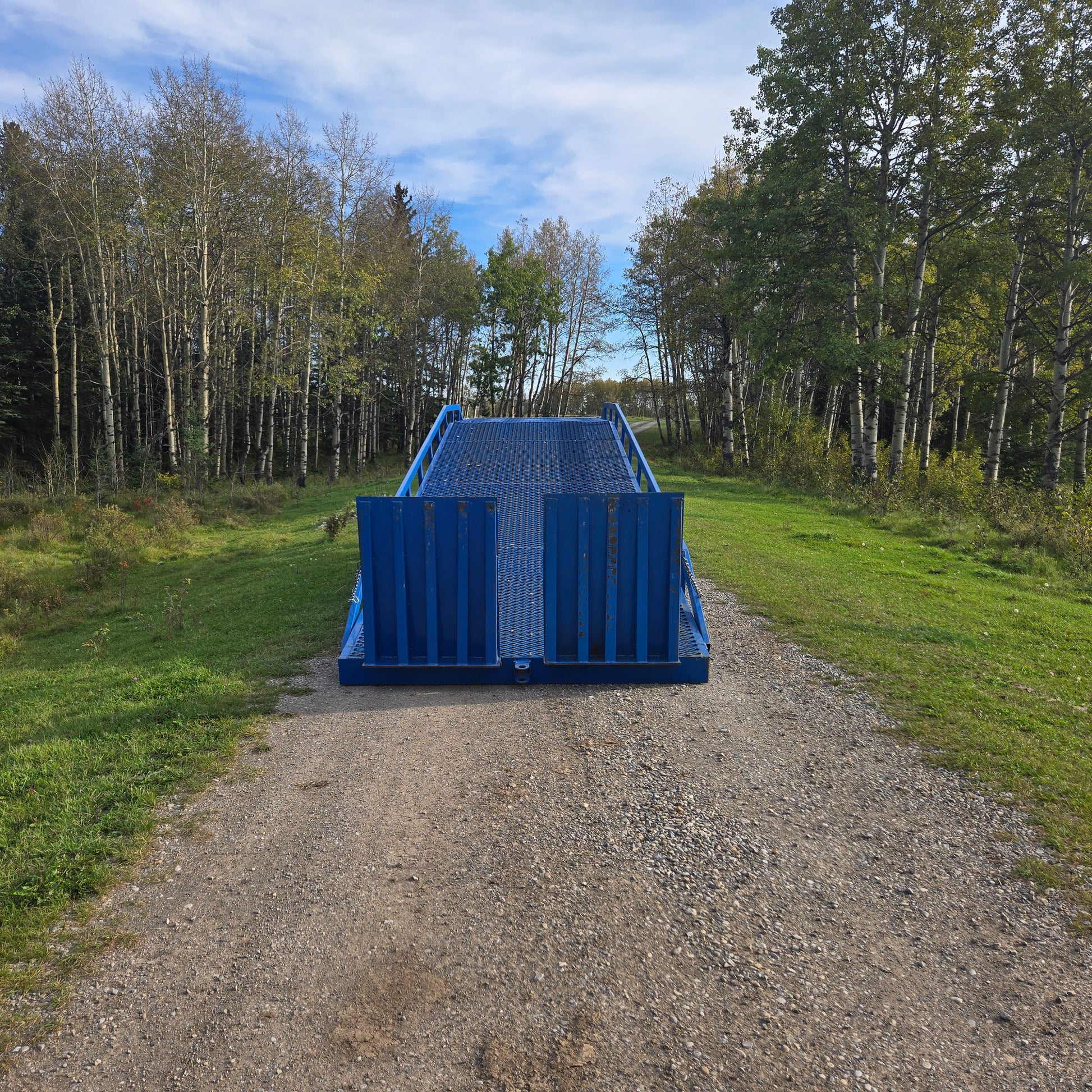 Twelve ton mobile loading ramp front view showing blue heavy duty steel ramp placed on gravel path for forklift truck and container loading in Canada