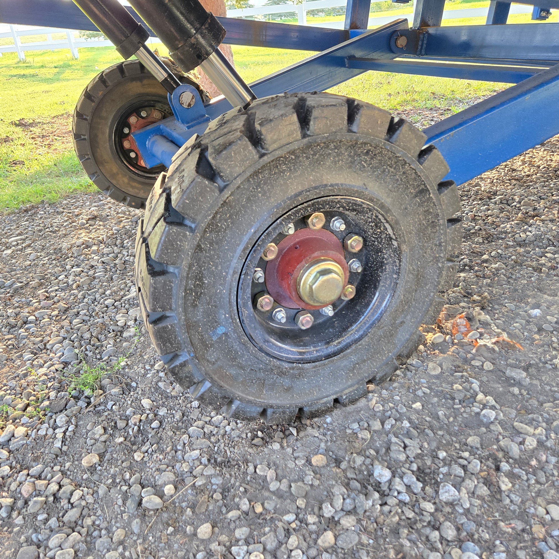 Close up view showing heavy duty solid rubber wheel and hydraulic support structure of twelve ton mobile loading ramp for forklift use in Canada

