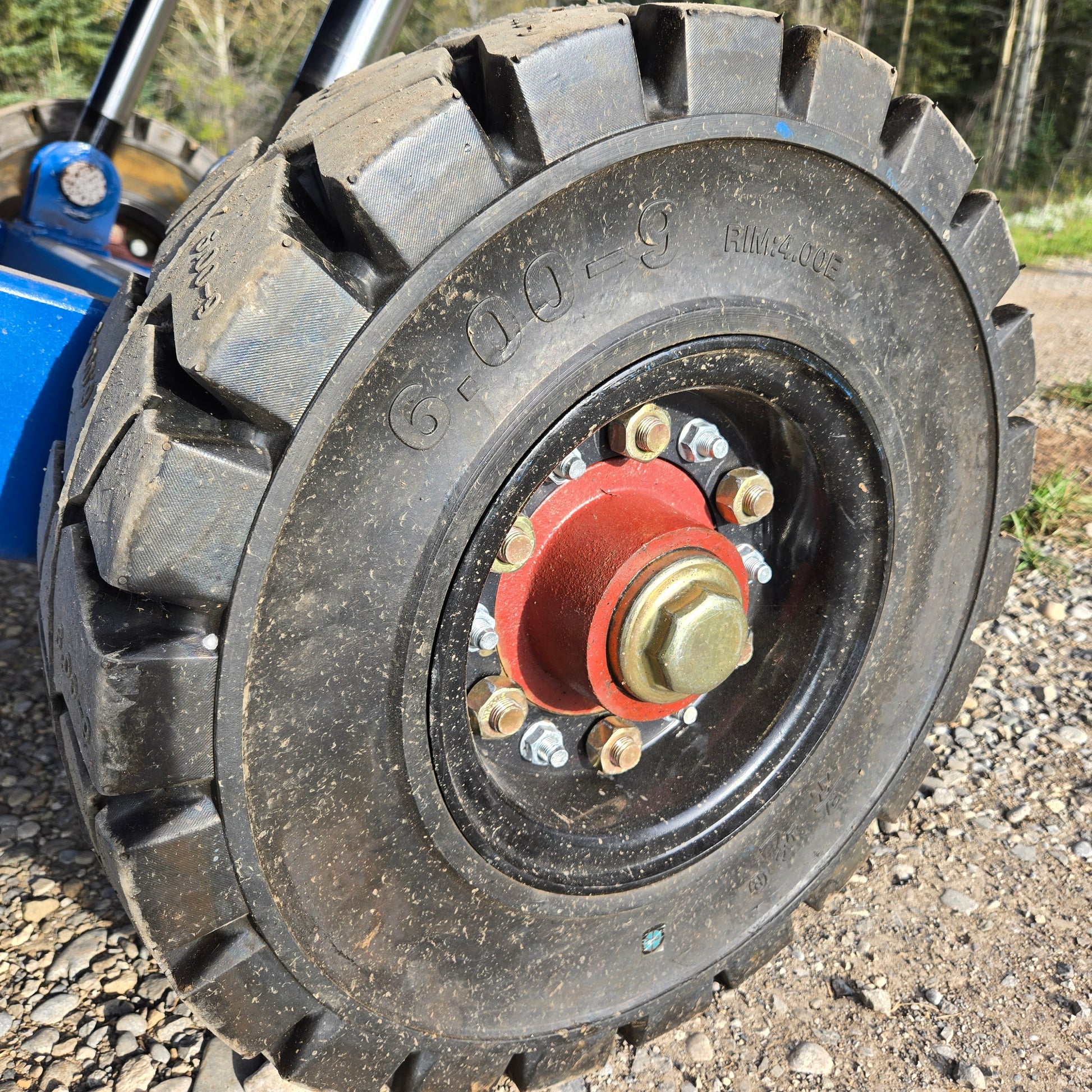 Close up view of heavy duty solid rubber wheel with red hub and steel bolts used on twelve ton mobile loading ramp for truck and forklift in Canada

