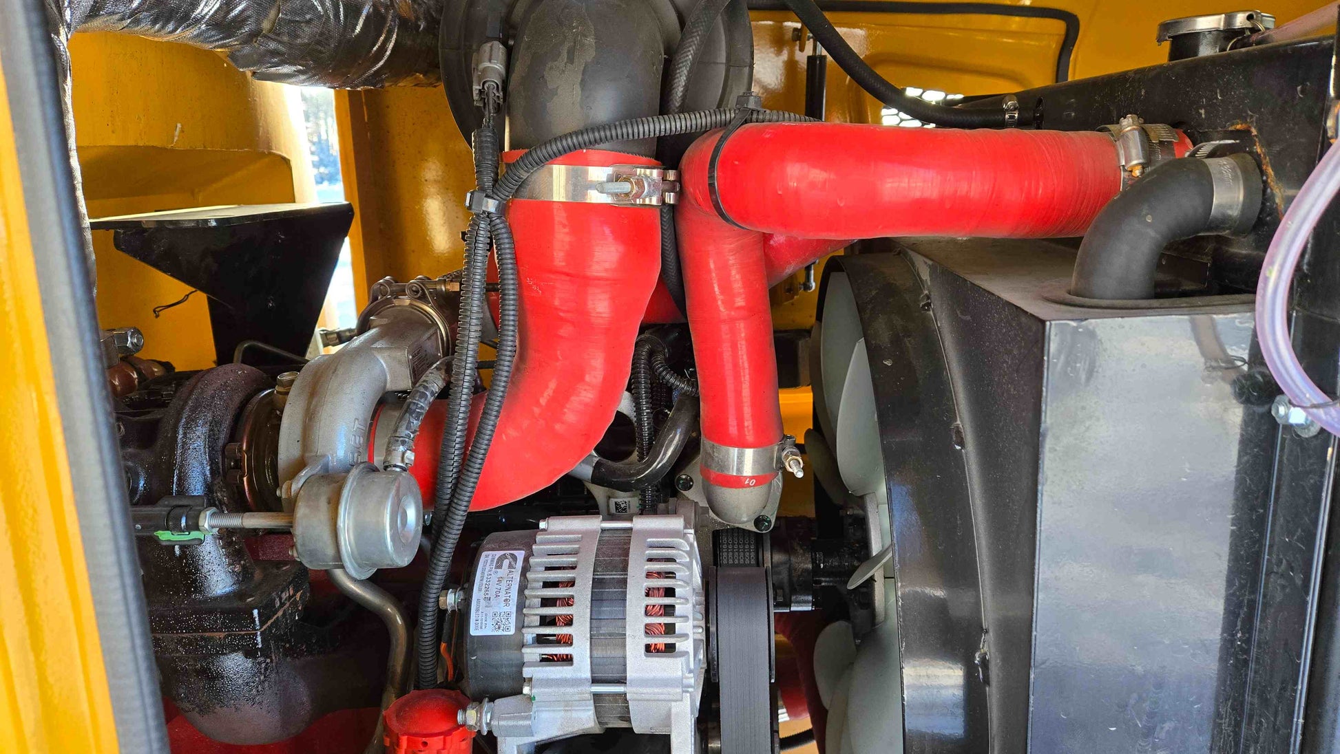 close up view of Cummins engine with red coolant hoses and alternator inside 2.5 ton compact wheel loader JT5WL2500 in Canada showing power and performance

