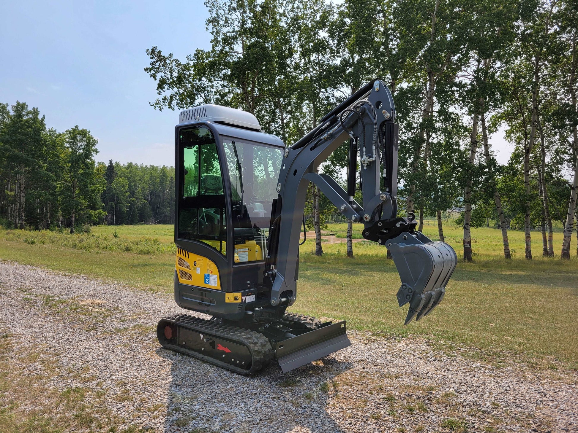 2 ton mini digger full cab model on gravel path in Calgary Alberta available for rent for landscaping and light construction projects

