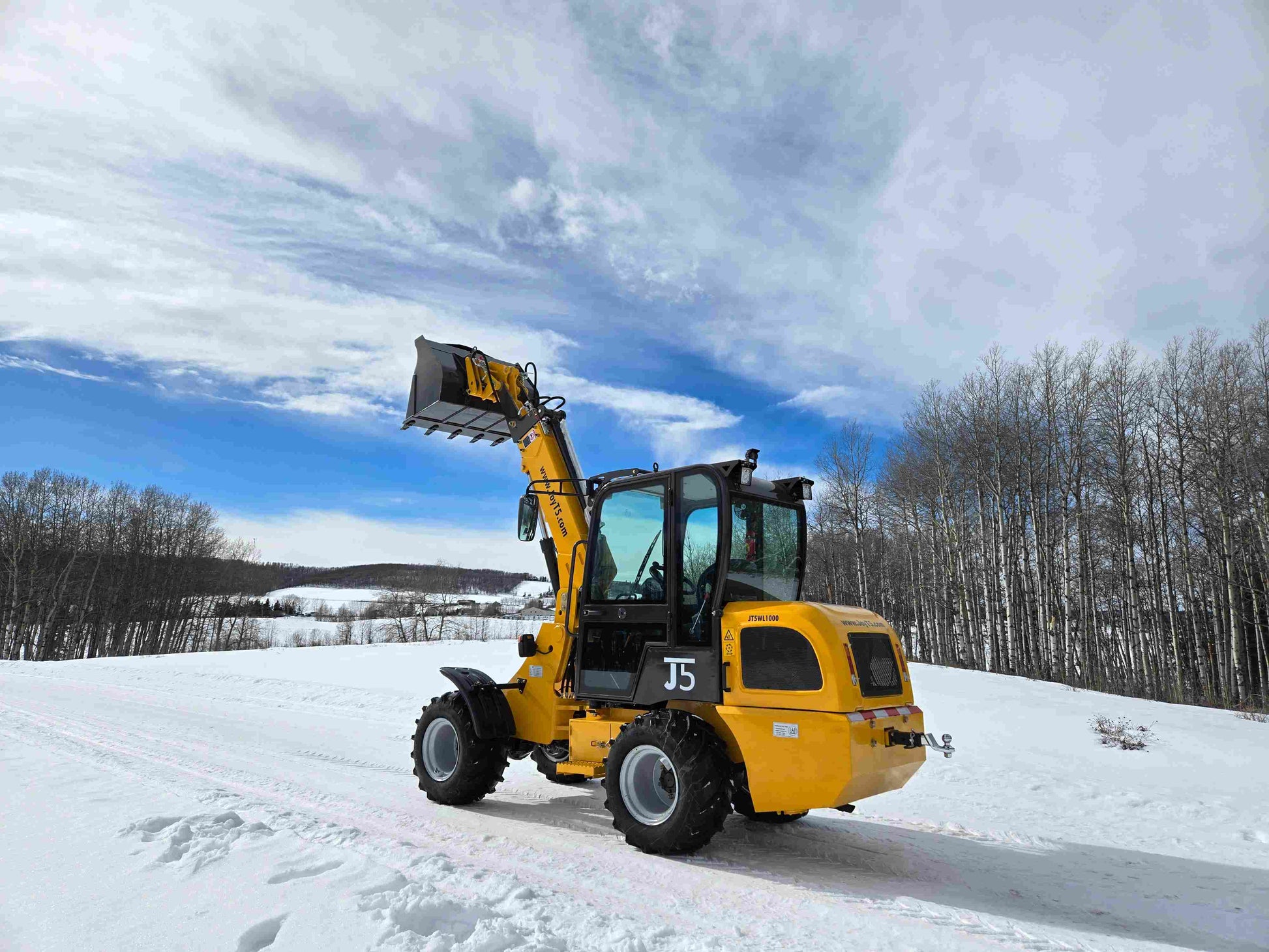 JT5WL1000 compact wheel loader 1 ton 2200 lbs rear angle with bucket lifted in snowy landscape