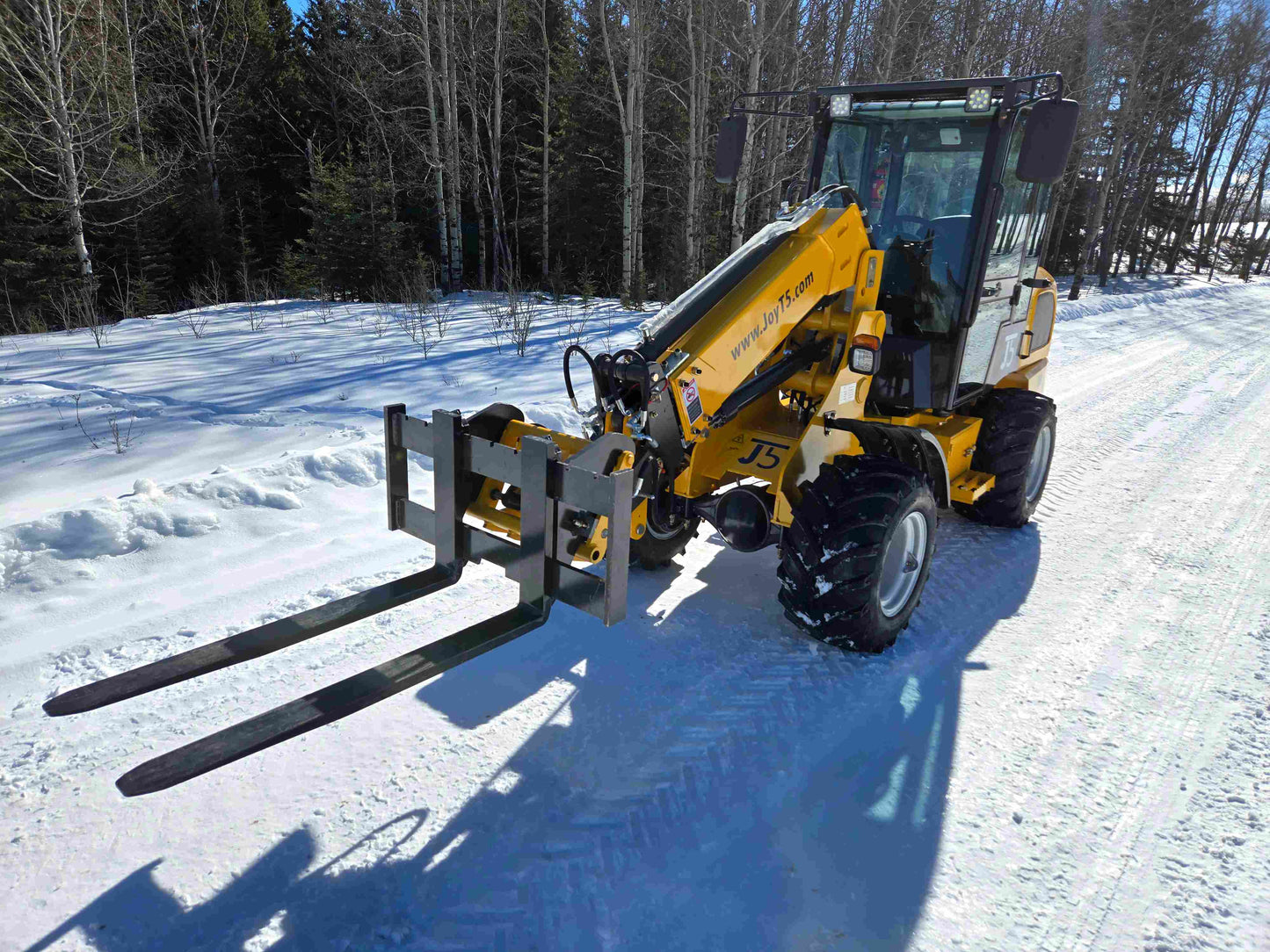 JT5WL1000 compact wheel loader 1 ton 2200 lbs with pallet fork attachment front angle view on snowy ground