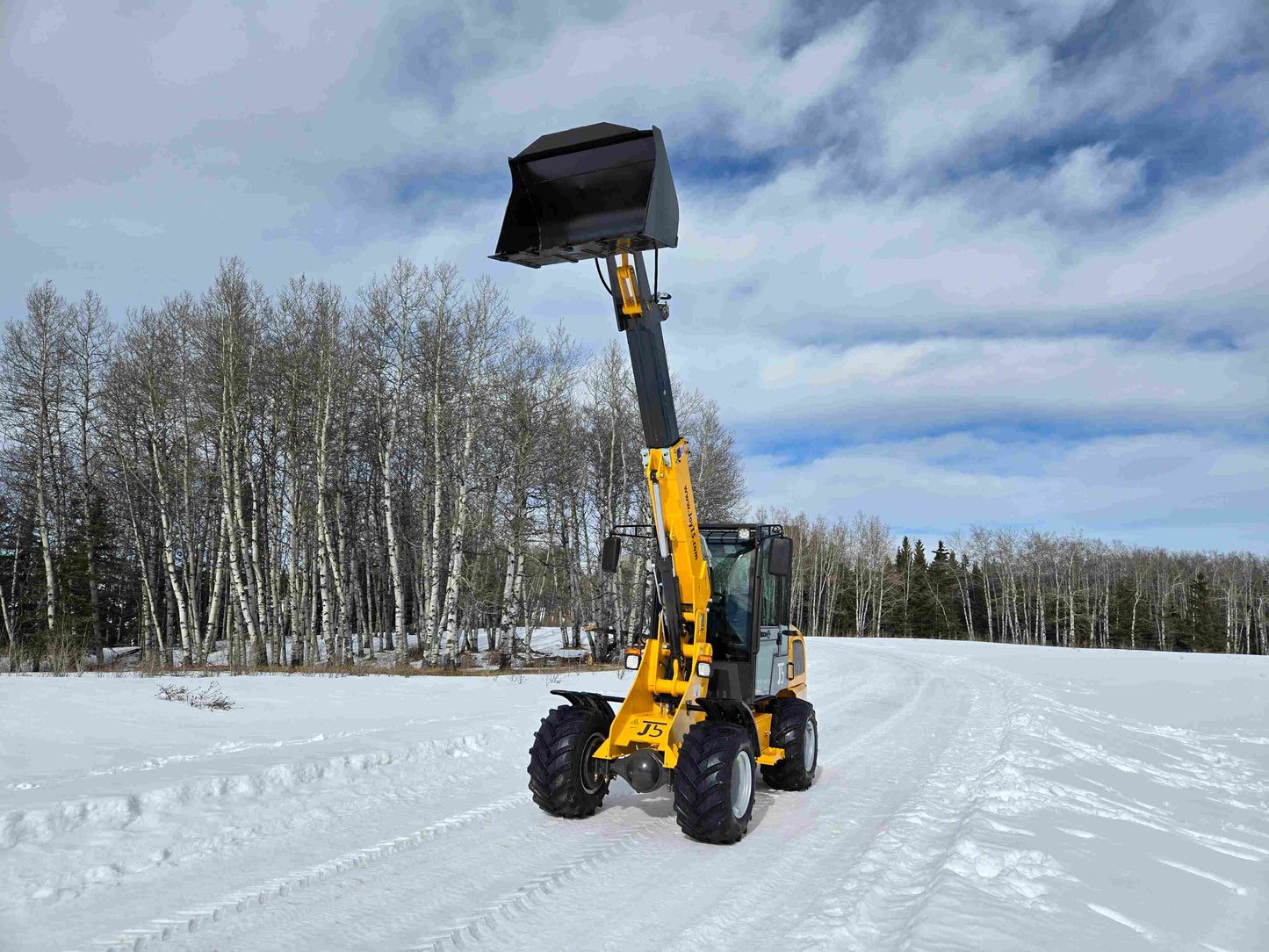 JT5WL1000 compact wheel loader 1 ton 2200 lbs front angle view with telescopic boom extended and raised bucket in snowy field