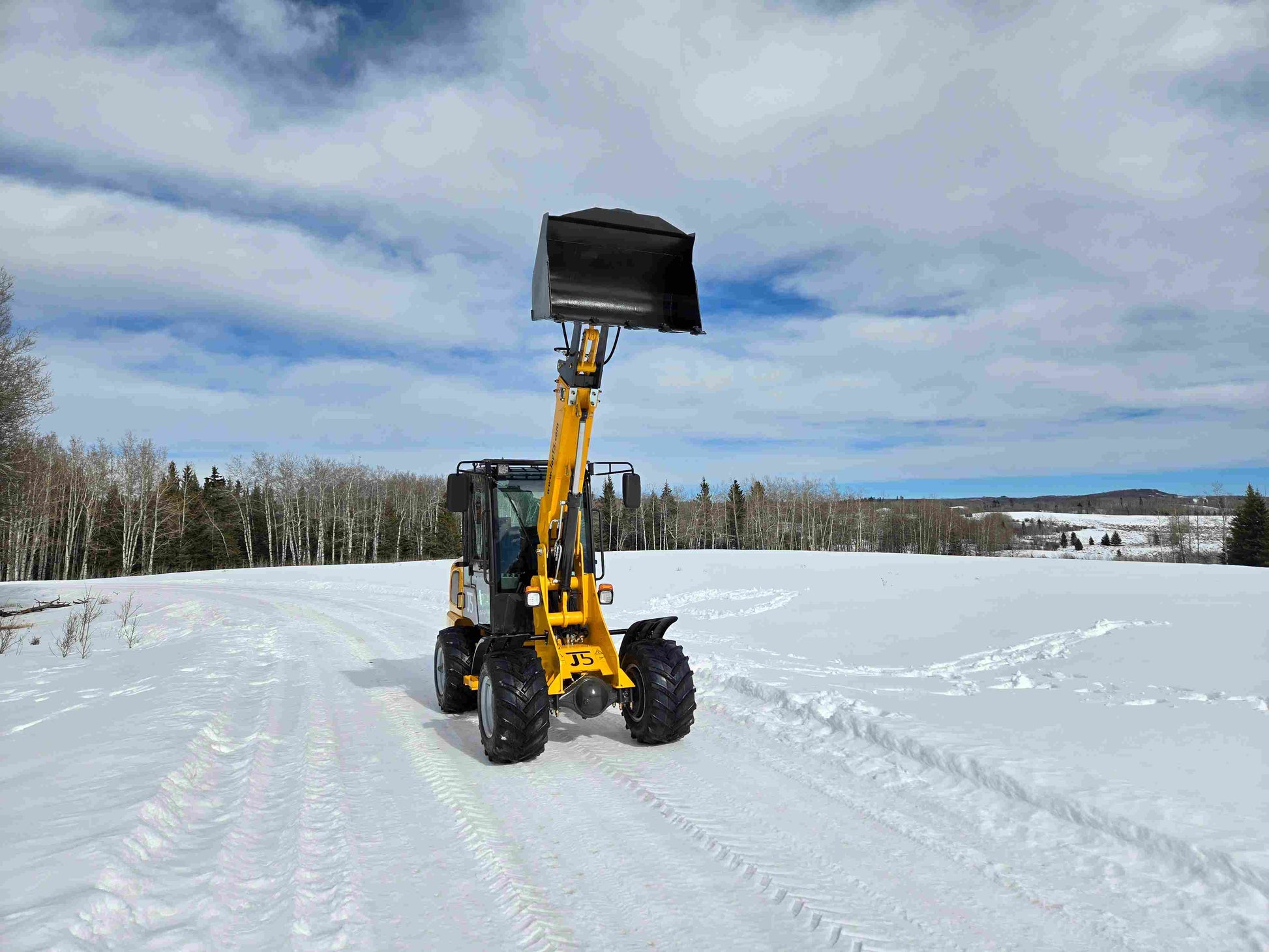 JT5WL1000 compact wheel loader 1 ton 2200 lbs front view with bucket raised on snowy road