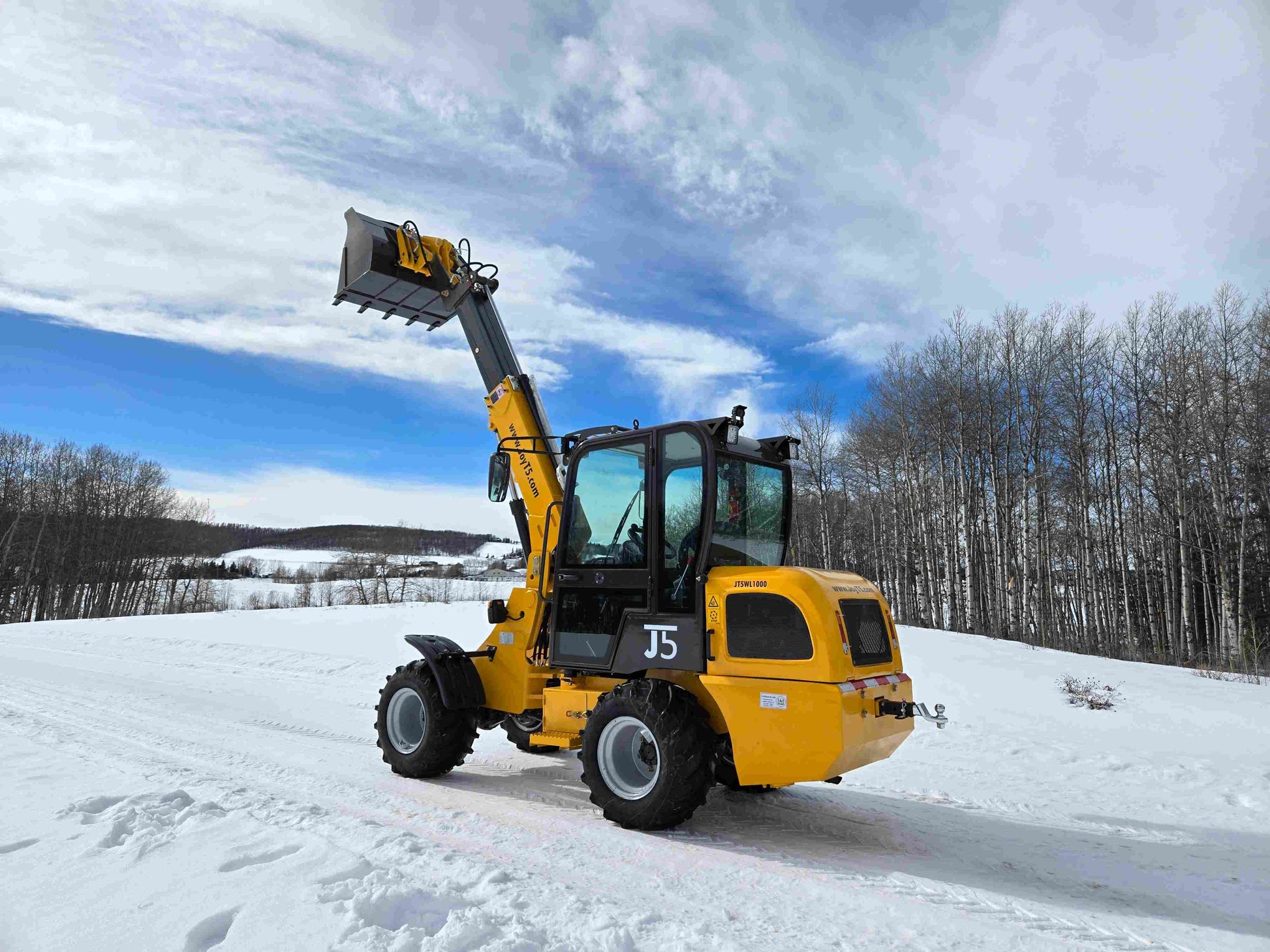 JT5WL1000 compact wheel loader 1 ton 2200 lbs rear side angle view with raised bucket in snowy field