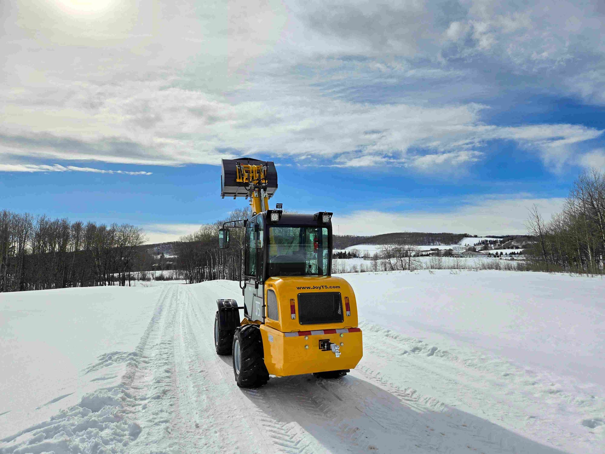 JT5WL1000 compact wheel loader 1 ton 2200 lbs rear view with bucket lifted in snowy field