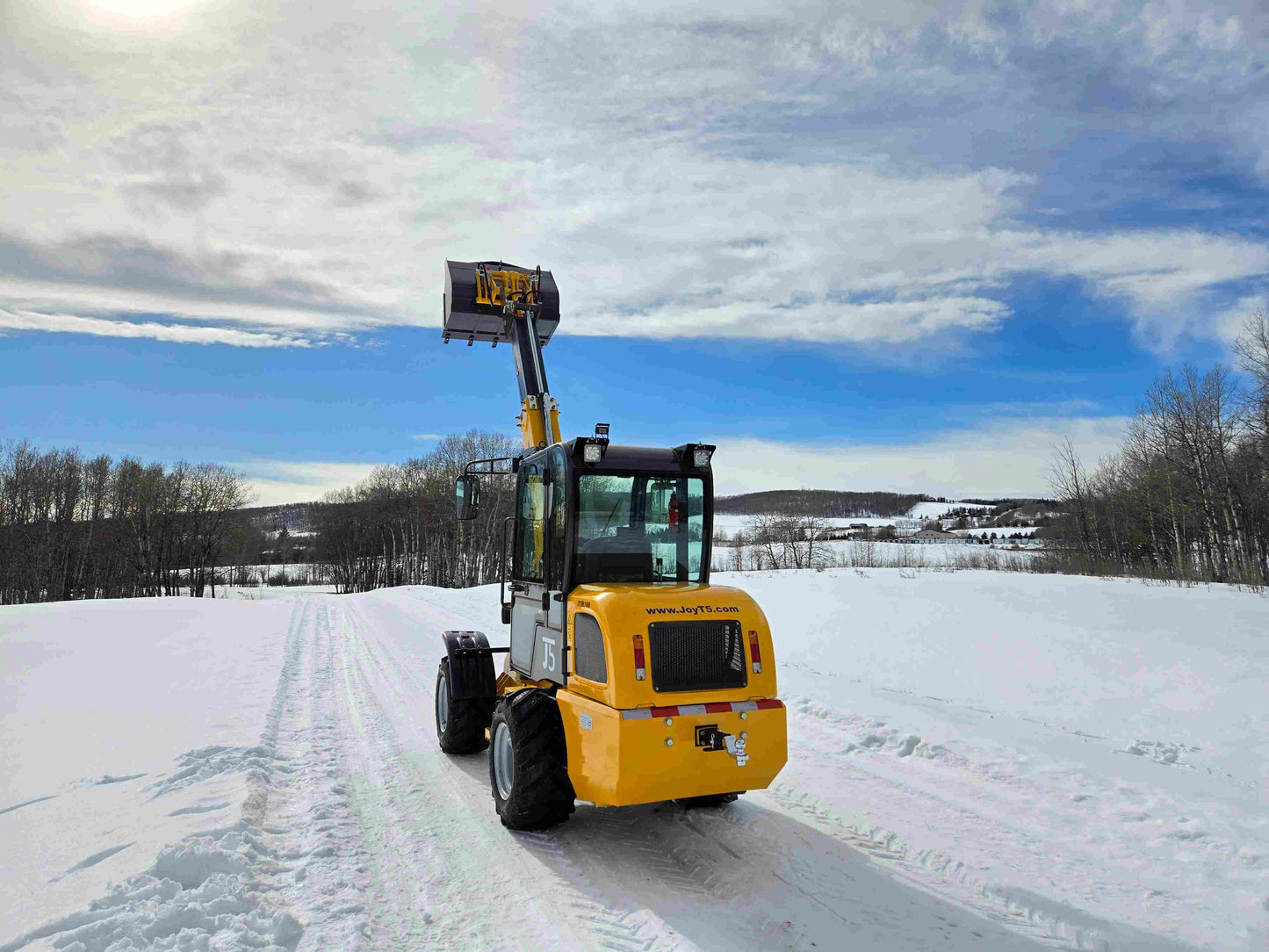 JT5WL1000 compact wheel loader 1 ton 2200 lbs rear view with raised bucket working in snowy field