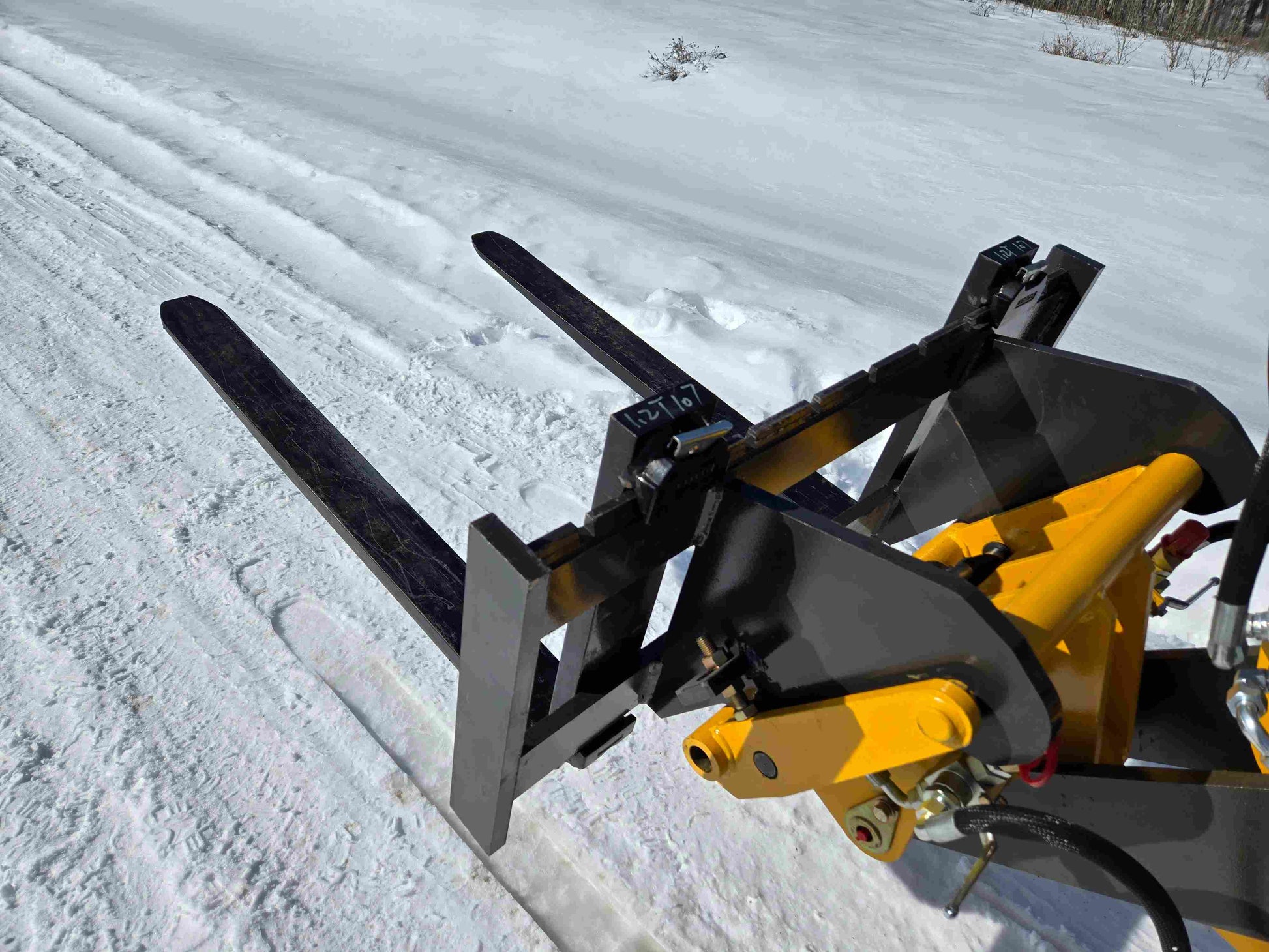 JT5WL1000 compact wheel loader with pallet fork attachment extended forward on snowy road