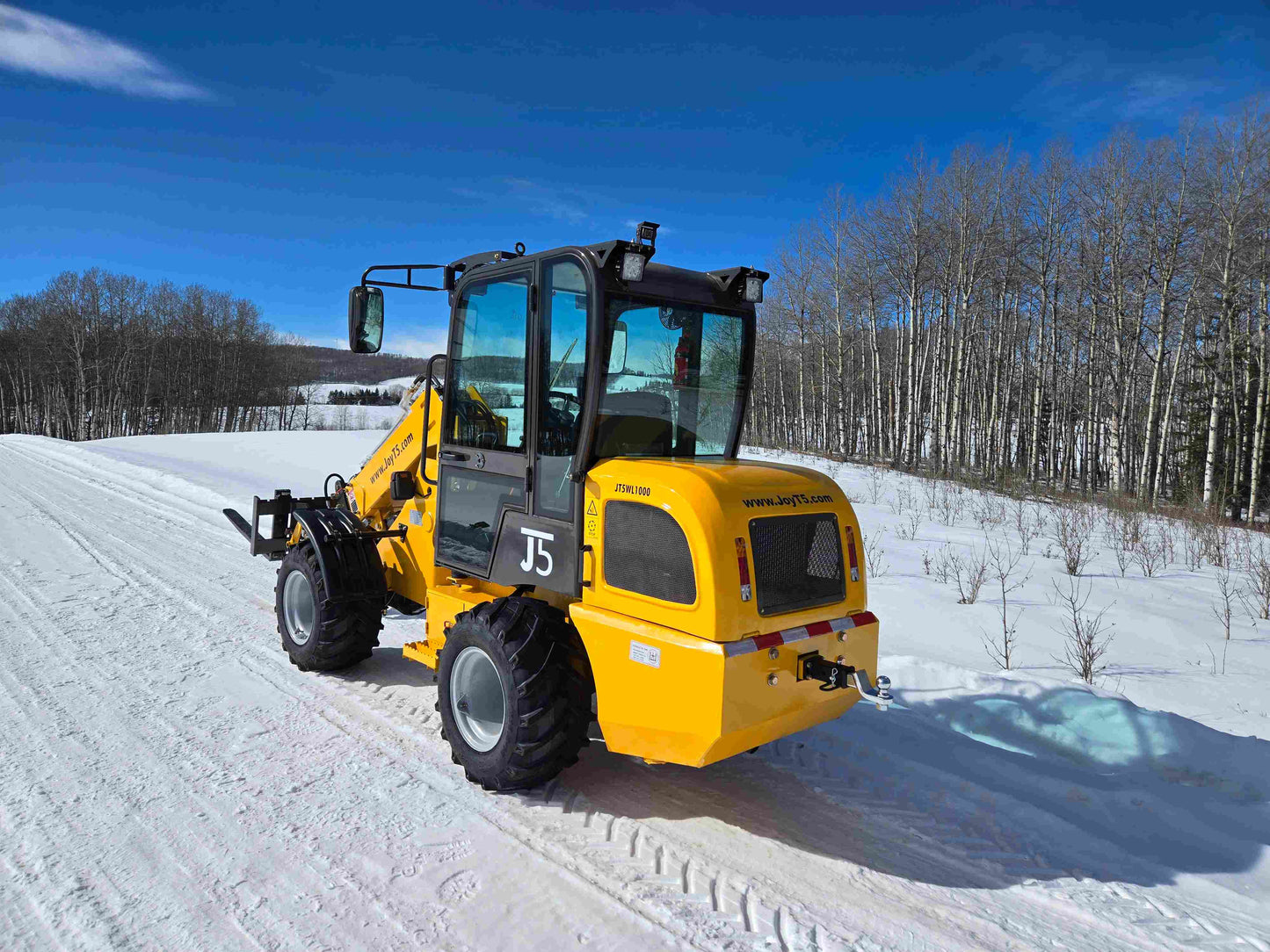 JT5WL1000 wheel loader rear view on snowy field with pallet forks and engine cover