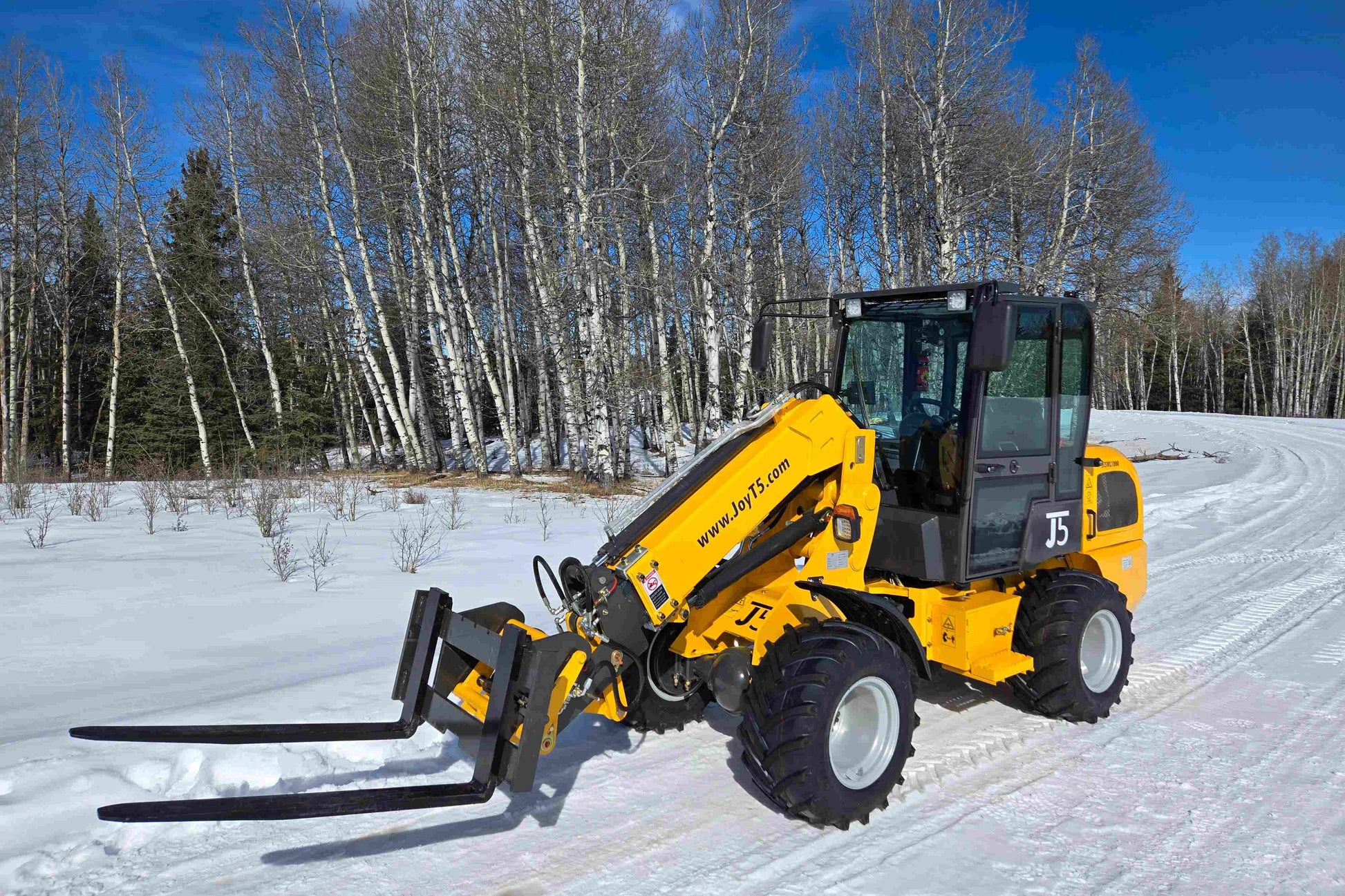 JT5WL1000 compact wheel loader with pallet fork attachment in snowy forest